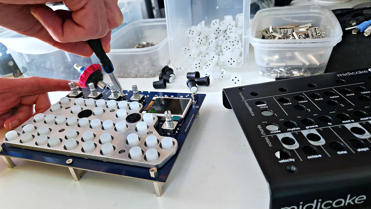Hands tightening a knob onto a Midicake ARP circuit board, next to a finished top panel
