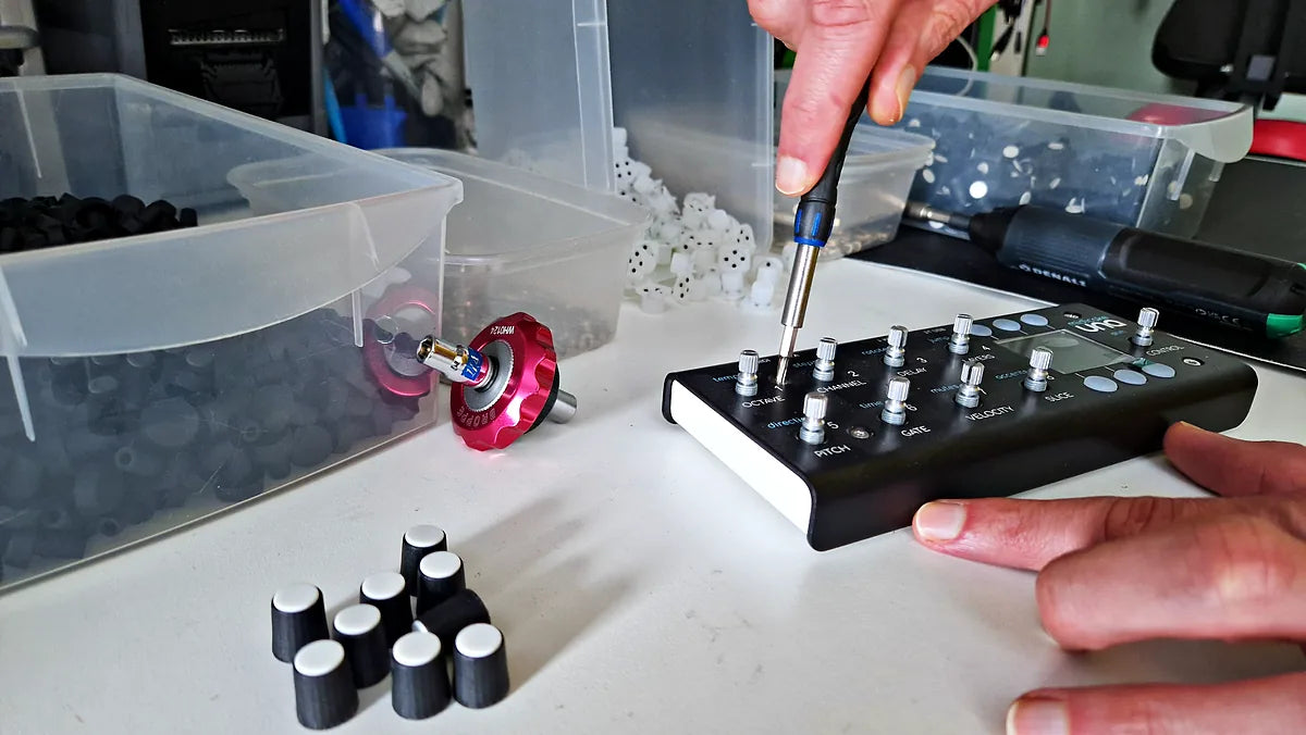 Hands fitting a knob to a Midicake UNA with a torque driver on the workbench
